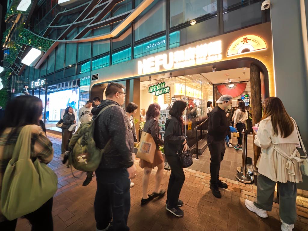 3月13日，在一內地面食品牌位于香港銅鑼灣的門店前，顧客排隊等候進店用餐。新華社記者 褚萌萌 攝