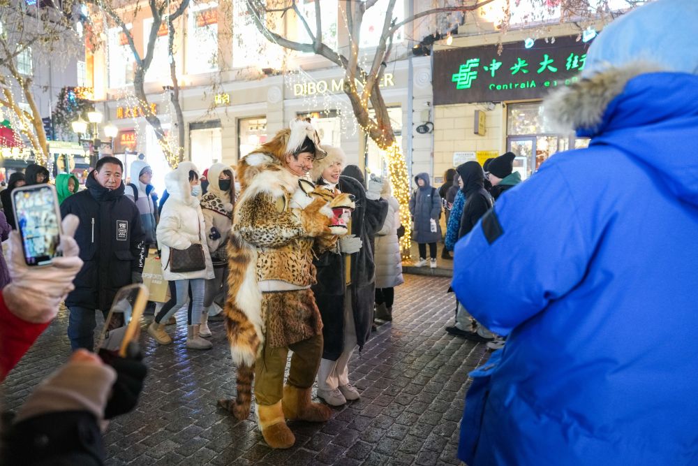 在哈爾濱市道里區，游客在中央大街上和身著特色服飾的當地人合影（2024年1月3日攝）。新華社記者 謝劍飛 攝