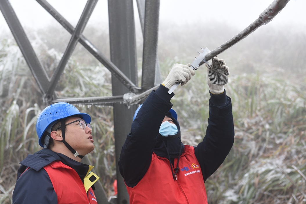 南方电网广东韶关供电局运维人员测量覆冰线路模拟导线的覆冰厚度。（叶高杨 摄）