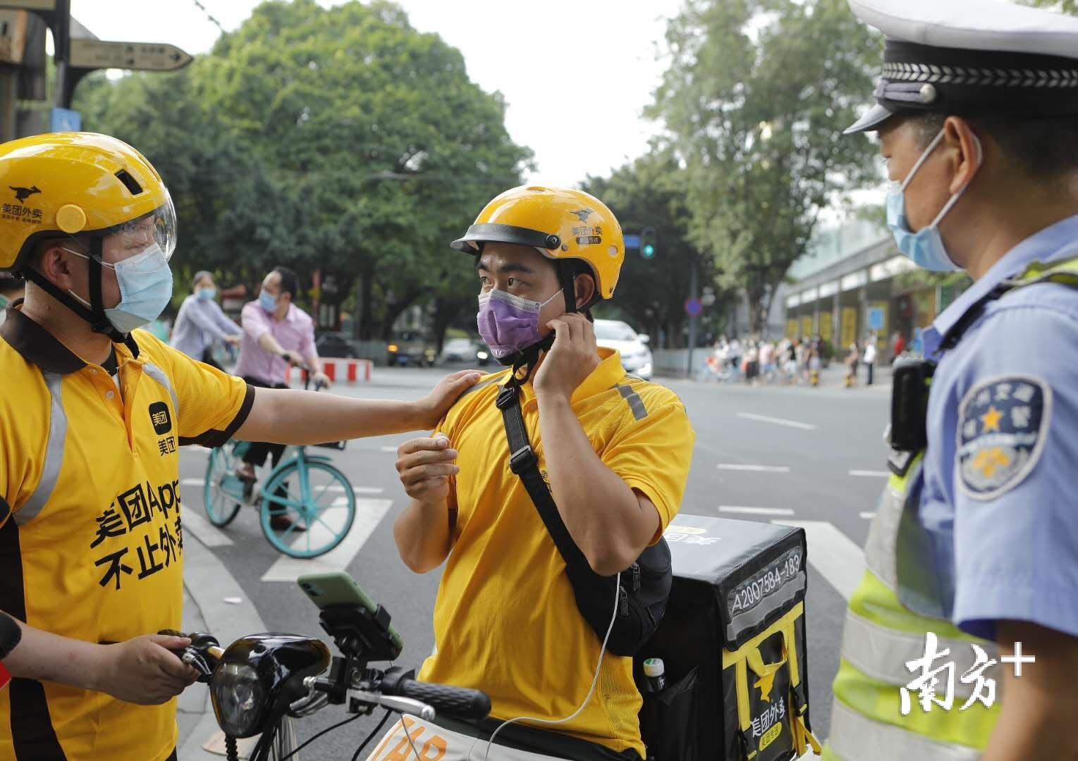 在馬路現場,交警對外賣騎手進行安全佩戴頭盔勸導.