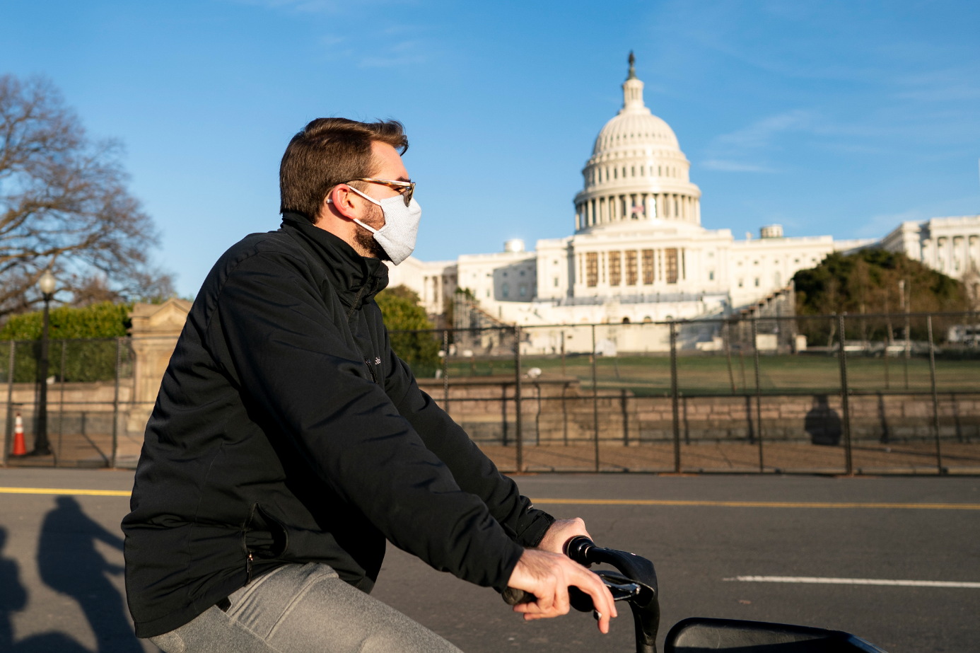 在美国首都华盛顿，一名戴口罩的男子骑车经过国会大厦。新华社发