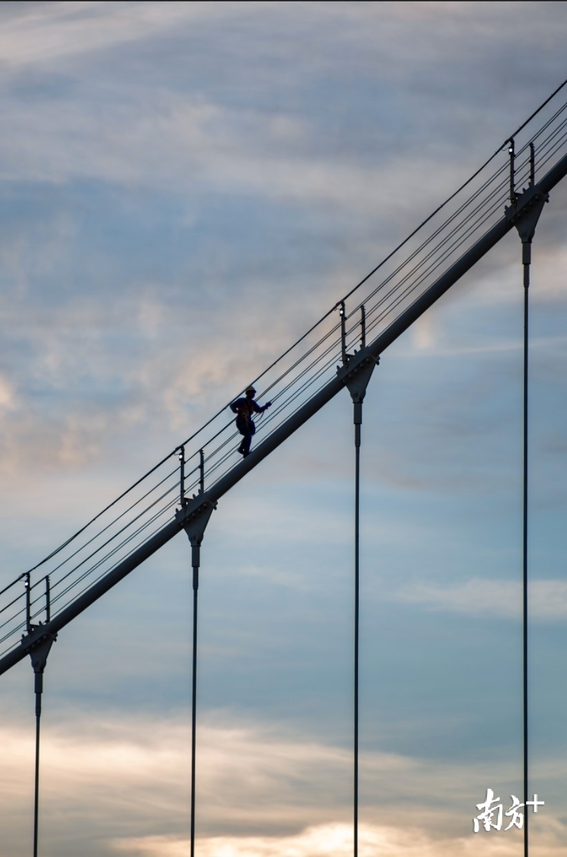 9月25日，珠海白石桥上，有工人顺着桥体巨大的拉索往上攀爬，准备去修理塔顶的桥灯。西风瘦马 摄