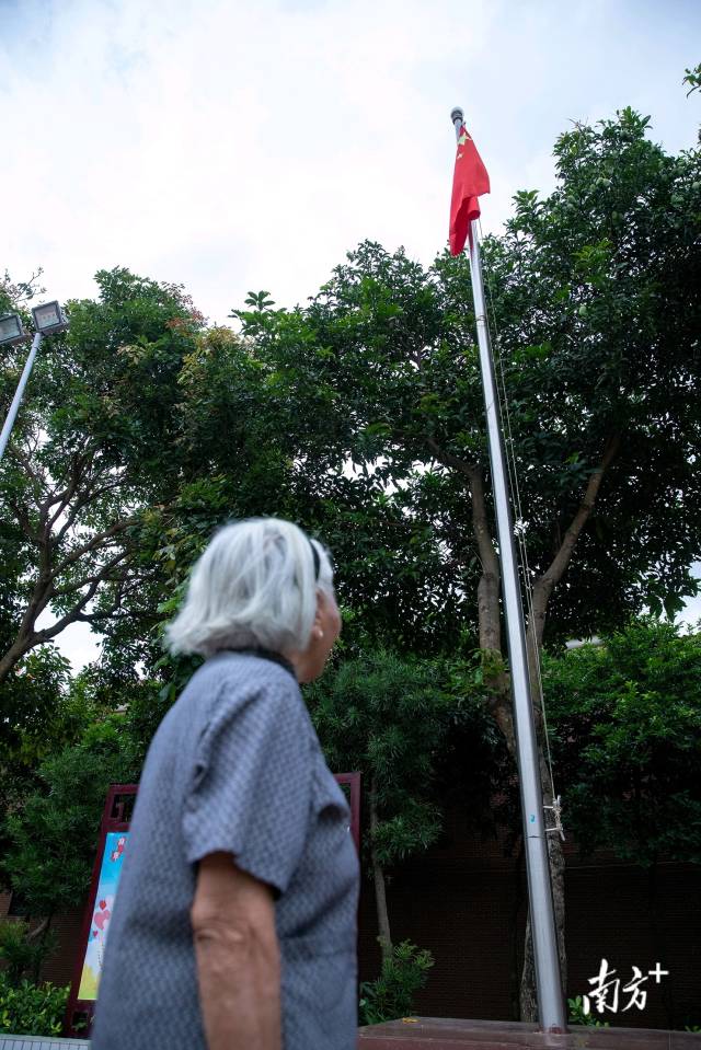 梁才英奶奶在城家外村村委门口的国旗下