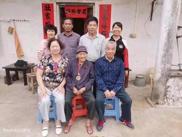 2021年春天，梁才英老人与三个儿子和儿媳妇在自家老房子门口合影留念。受访者供图