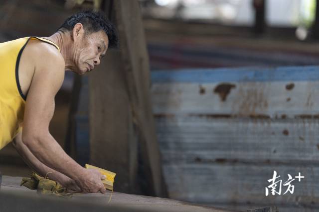 一名木工师傅用传统的拉直线方式量度船板。 