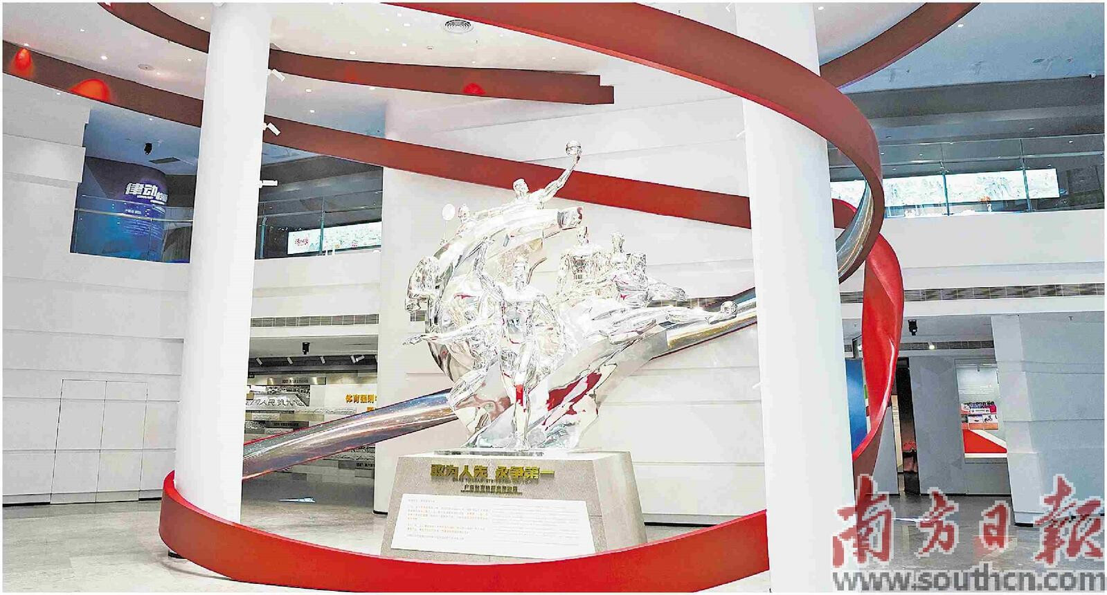 图为广东体育博物馆一楼大厅中心的主雕塑，以广东体育健儿为创作原型，立体诠释了“敢为人先，永争第一”的精神。