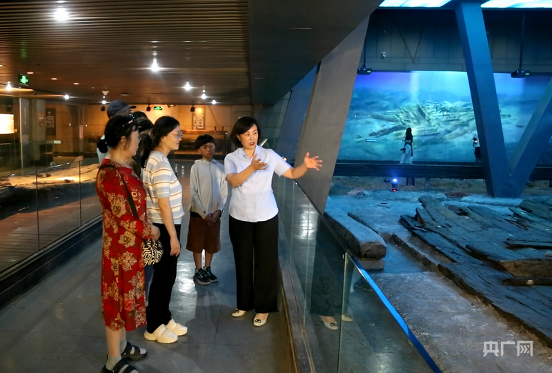 刘莉正在给游客讲解古船的来历（央广网记者 唐磊 摄）