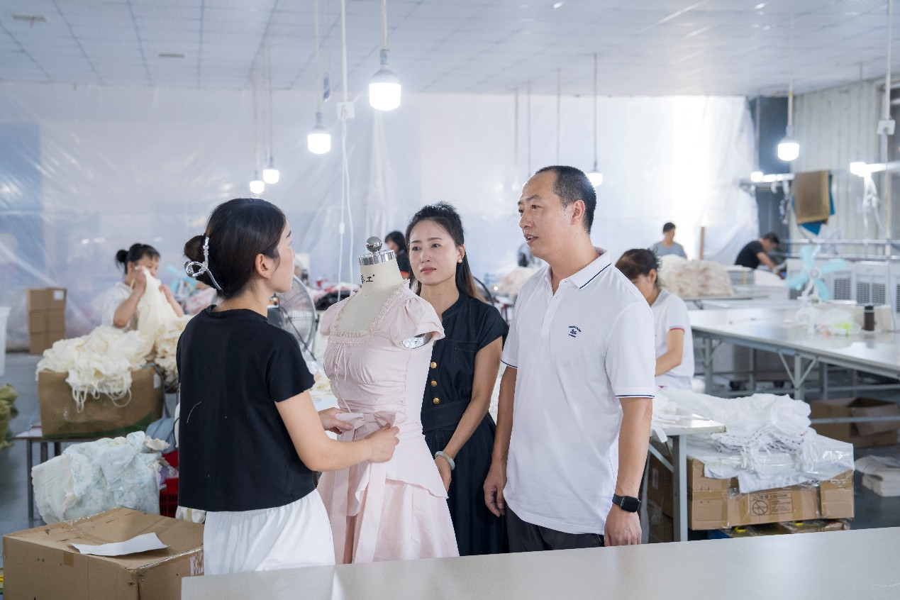 王博（右一）和妻子张玲（右二）与员工交流样衣款式。 陈勇|摄