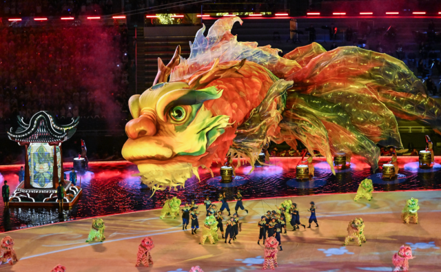 开幕式表演中,巨大的金色“鳌鱼”装置,在少年武者的牵引下灵动遨游于场馆半空,如梦似幻、惊艳四座。图源:新华社 开幕式表演中,巨大的金色“鳌鱼”装置,在少年武者的牵引下灵动遨游于场馆半空,如梦似幻、惊艳四座。图源:新华社