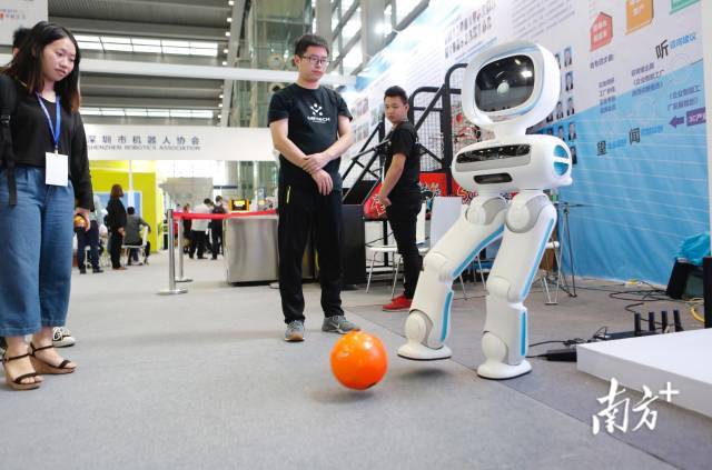 优必选的机器人在和人互动踢球。