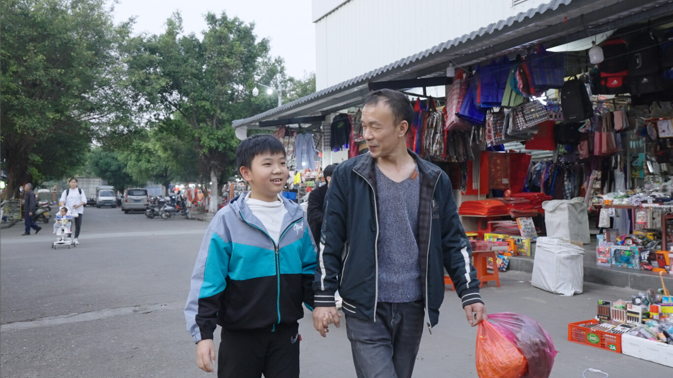 来自河南的农民工杨占业接送孩子放学，他们一家已经在佛山生活了13年。