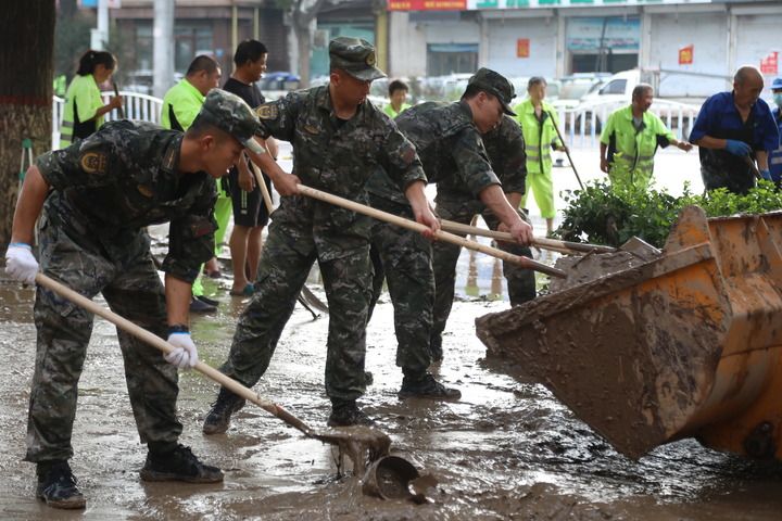 武警河北总队保定支队官兵在涿州市城西107国道沿线清理淤泥（8月5日摄）。新华社发（王红强 摄）