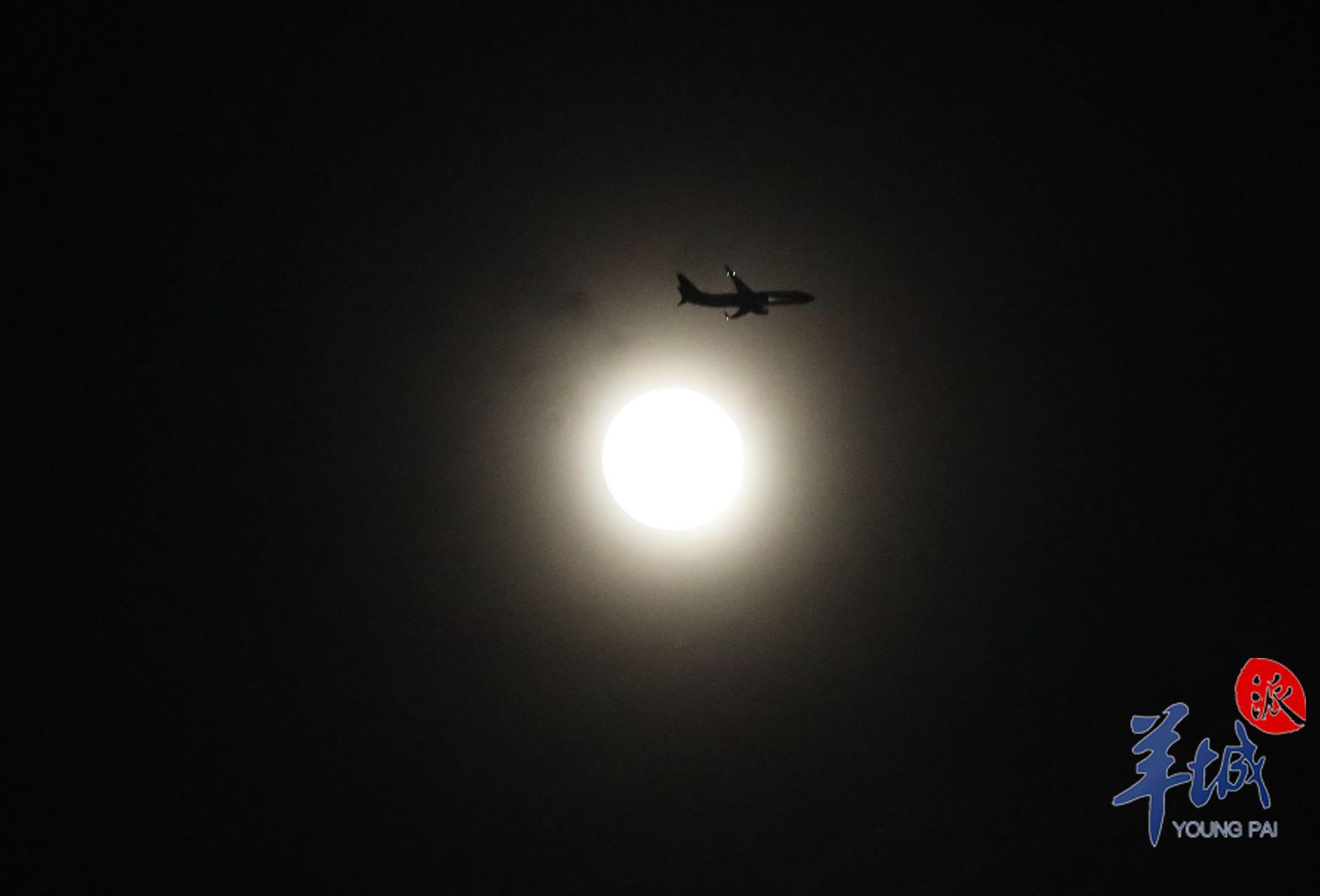 资料图：月亮透过朦胧云层出现在广州夜空，一架民航客机恰好经过。羊城晚报全媒体记者 梁怿韬 摄