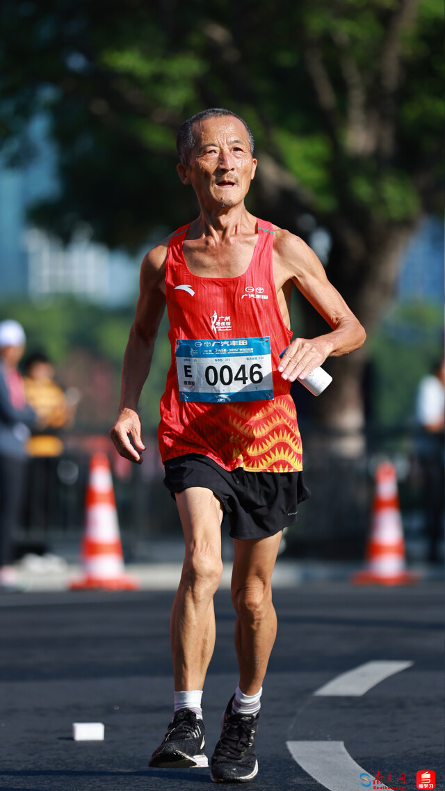 2025年12月21日，广州马拉松赛道上，一位头发花白的老年跑者正坚定前行。肌肉线条分明的手臂，尽显长期坚持运动的力量感。