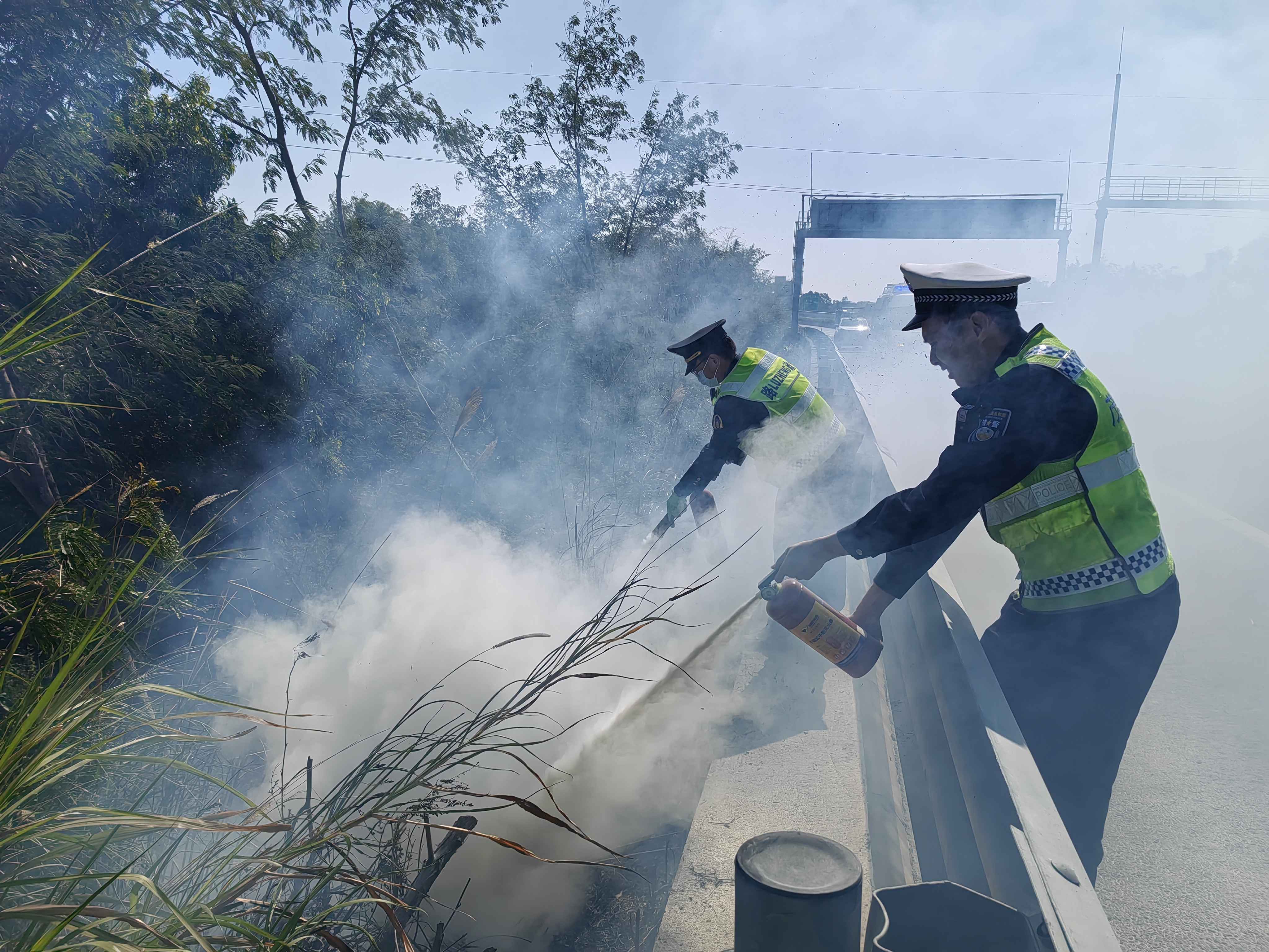 在包茂高速往广西方向某处,路政队员张潇、黄志翔奋力灭火。