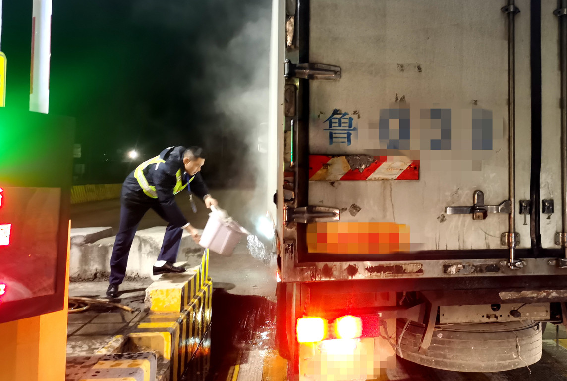 在包茂高速信宜南站,工作人员罗明汶将冷水浇到冒烟轮胎处,消除隐患。