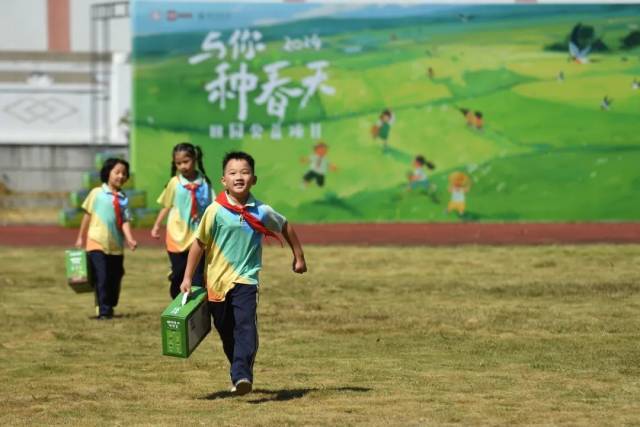 ▲黄土咀小学的孩子们拿着种植礼盒奔跑。