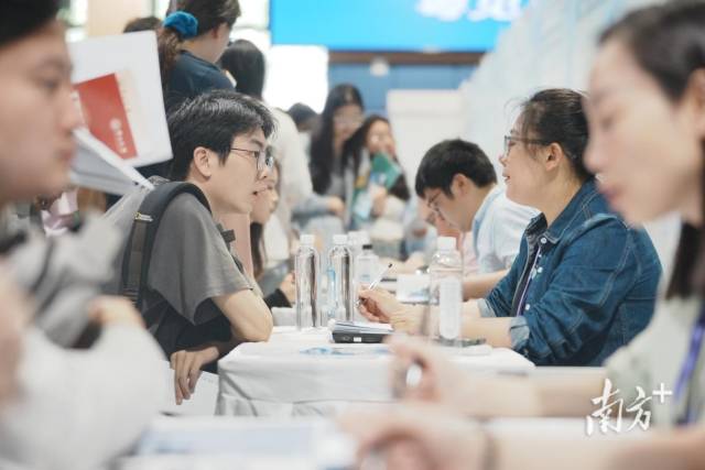 “百万英才汇南粤”武汉招聘会现场火爆，企业招聘展位座无虚席，面试洽谈对接需求。