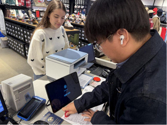 店员正在使用平板电脑为境外旅客开具退税单和发票。通讯员供图