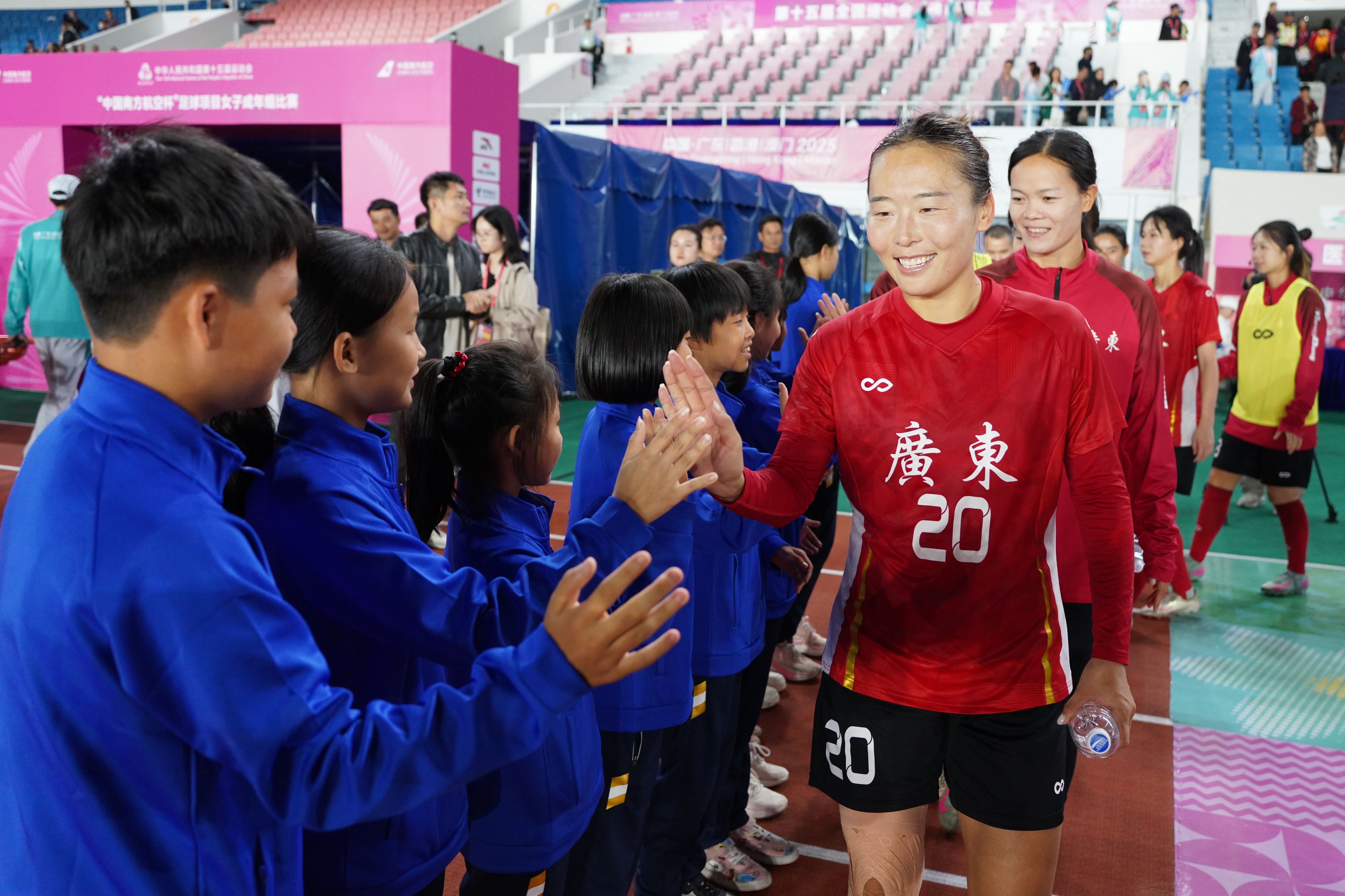 广东女足和小女足队员们一一击掌,欢迎她们来到全运会赛场。