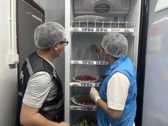 监管人员检查配餐公司,查看其是否按食品安全要求规范打餐、妥善存储食材。