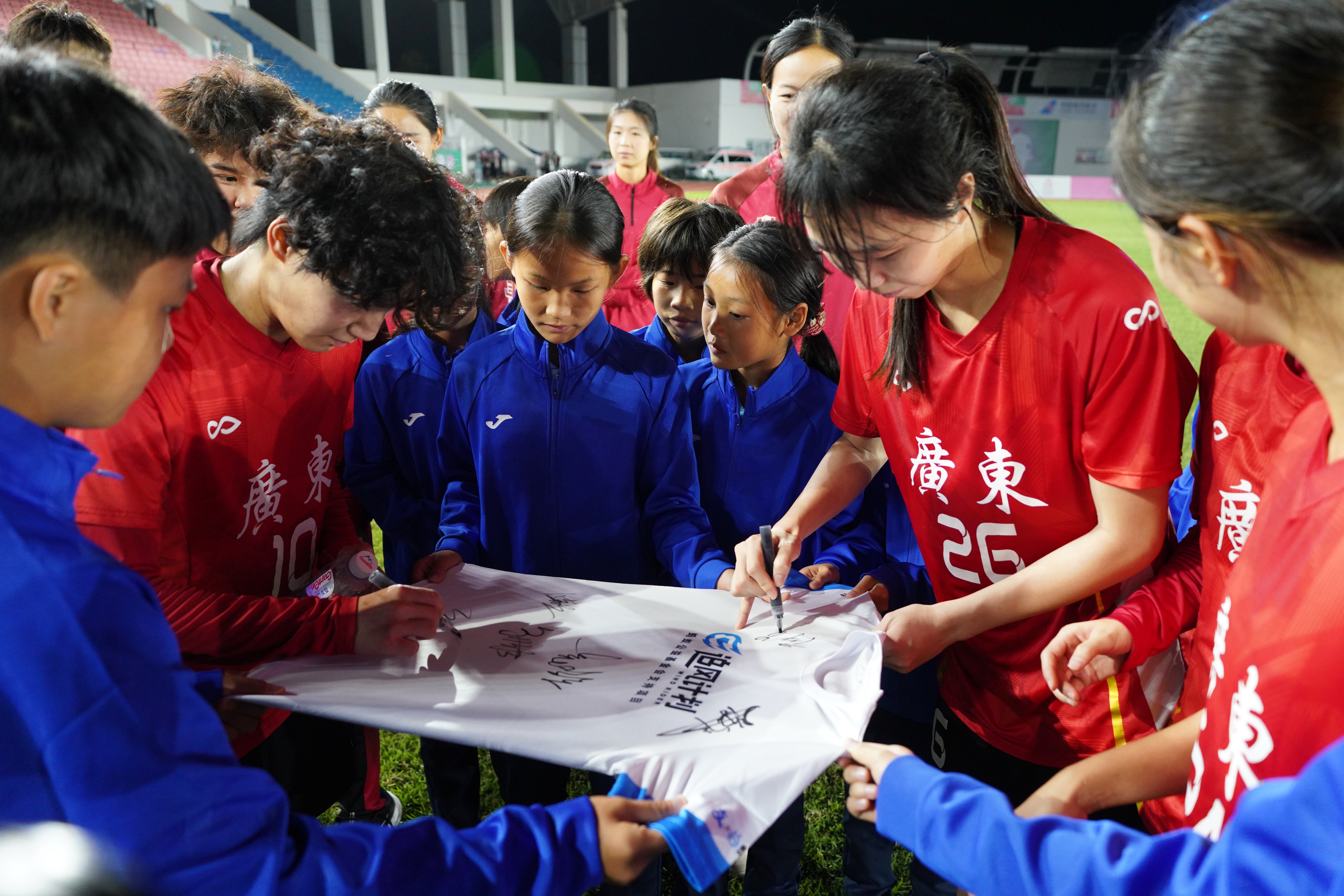 广东女足在女孩们“追风计划”的球衣上签名。