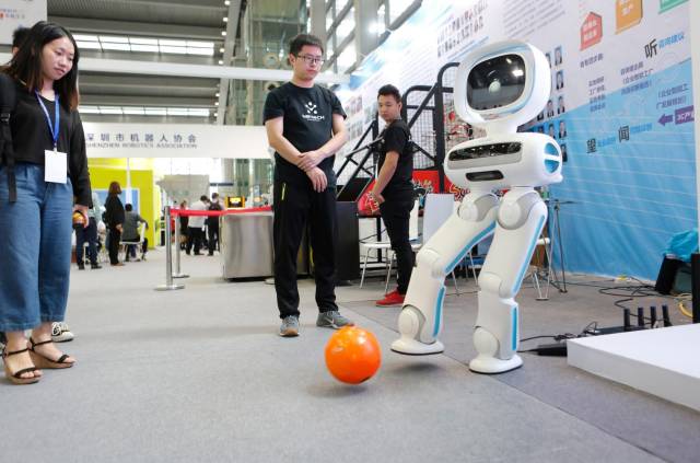 优必选公司的机器人正在和人互动踢球。
