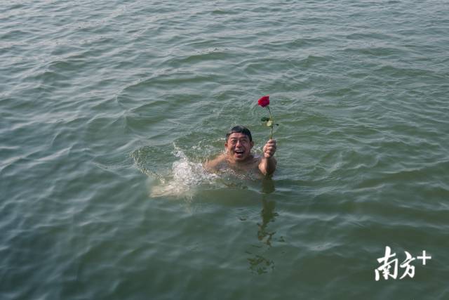 4月9日，东湖，一位游泳爱好者在水中捡起一朵落水的玫瑰花，甚是高兴。