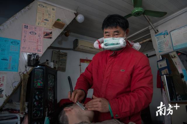 4月13日，得胜桥，一位理发师傅戴着自制的防毒面具为一位客人剃须。