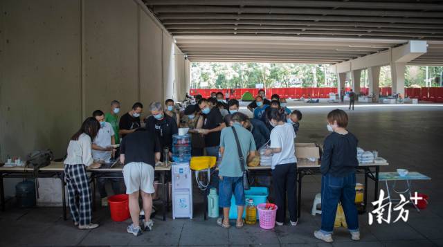 志愿者脑八（化名）和市民为广州大桥底围留宿者发放热饭，并登记他们的个人信息。