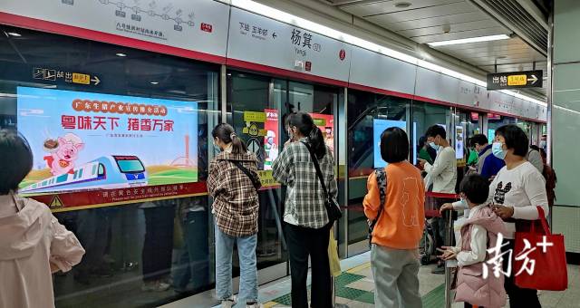 在五号线杨箕站，乘客在候车间隙观看灯箱广告。