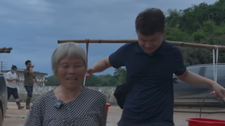 水灾刚过的怀集街头，记者遇到了要挑水上6楼的阿婆