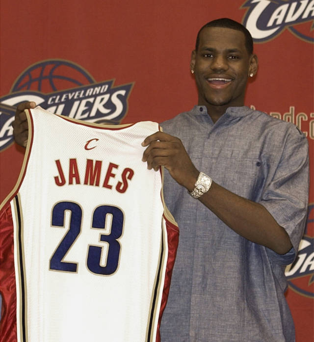 骑士在2003年NBA选秀大会上用状元签选中詹姆斯。图为詹姆斯在发布会上举着自己的23号球衣。