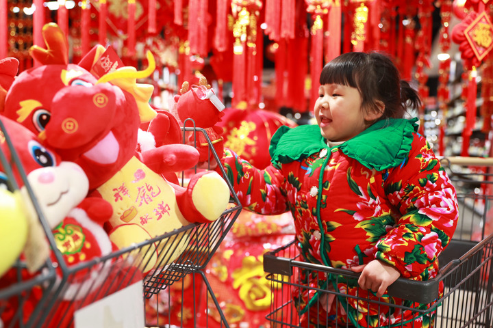 　　1月23日，在贵州省黔东南苗族侗族自治州岑巩县一家超市，小朋友在家人的带领下选购龙年毛绒玩具。新华社发（唐鹏摄）