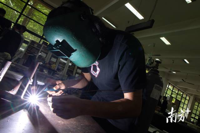 车架组成员张博文浩穿戴着装备，正在焊接车架上的部件。 
