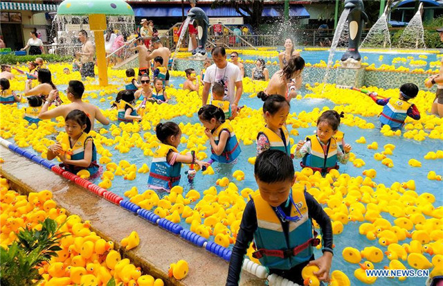 People have fun with yellow rubber ducks at Chimelong Water Park in Guangzhou