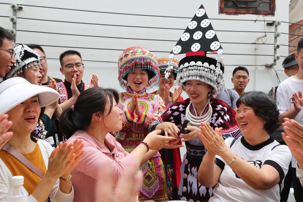 6月10日，在云南水富市两碗镇三角村，当地人向游客敬上苗家米酒。新华社发（狄廷秀摄）