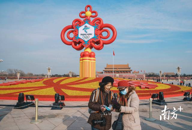 1月18日上午，游客们在天安门广场布置的“精彩冬奥”主题花坛前合影留念。 