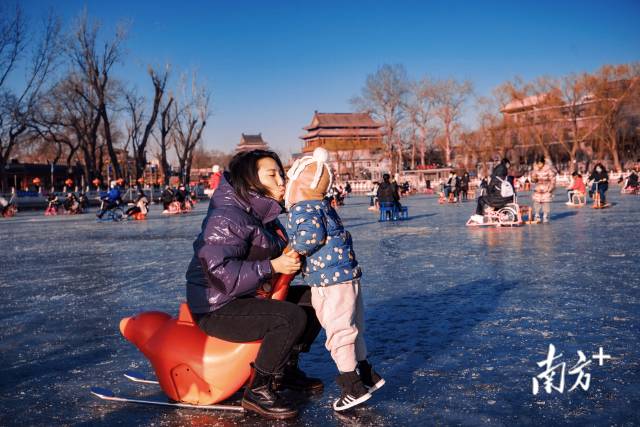 1月17日，北京什刹海冰场，一位带孩子玩冰车的家长亲吻自己的小孩。 
