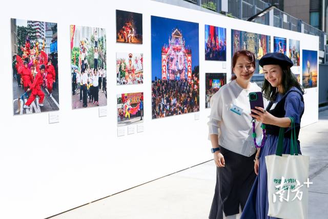 在“水·融”——粤港澳大湾区人文摄影展，众多嘉宾和观众在拍照留影。