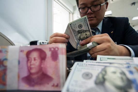 An employee at a bank counter in Nantong, Jiangsu province, counts renminbi and dollars. (Photo/China Daily)