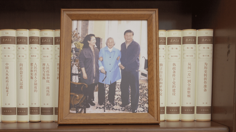 习近平办公室的书架上放着一张照片，照片中他和爱人彭丽媛搀扶着母亲。