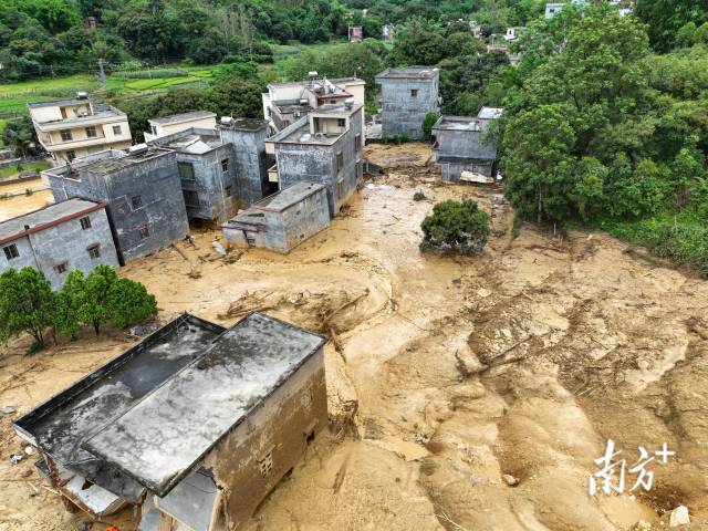 滑坡现场泥浆、树木残骸铺满地面，几栋房屋被泥沙侵袭。颜志雄 摄