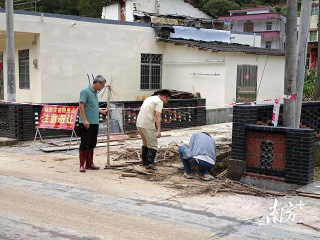 6月16日下午，驻守在滑坡现场的村干部正清理村庄周边杂物。颜志雄 摄