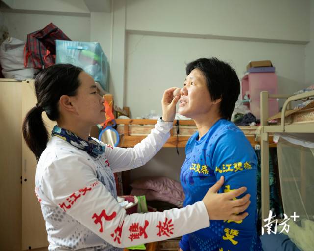 队员关佩诗为队员董爱丽擦拭防晒。女队员们既爱拼搏也爱美。