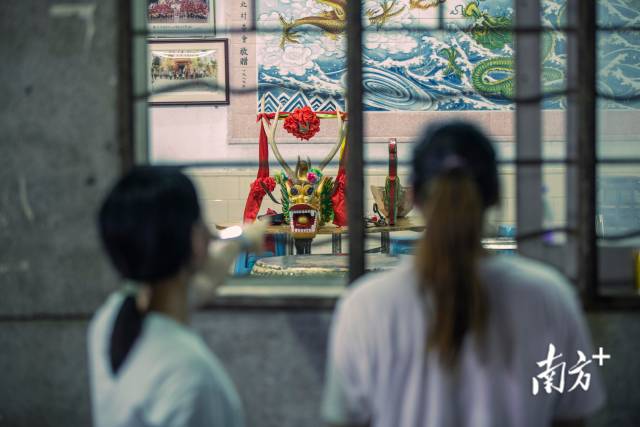 佛山南海，李雪和队友隔着窗子欣赏当地的龙船龙头。