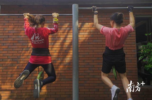 队员们在腰间挂上重物进行引体向上锻炼力量。