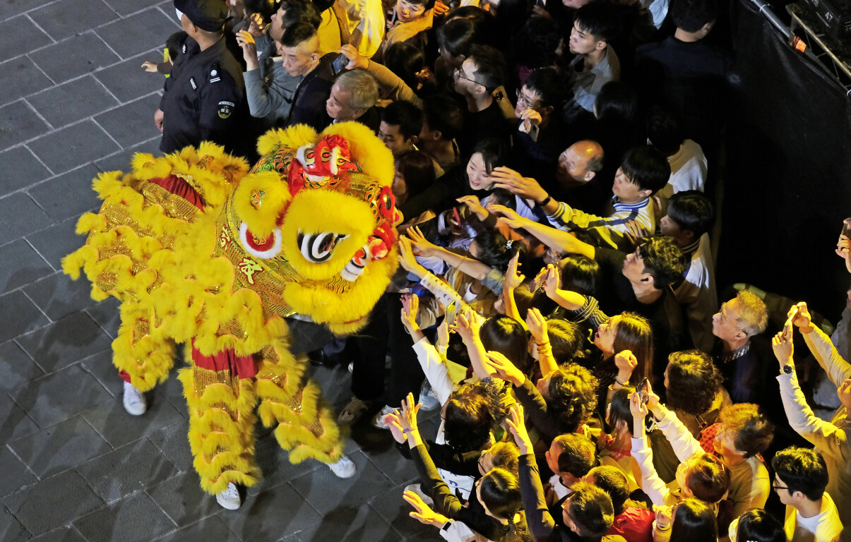 Visitors reach out to touch the lion at a cultural celebration, Small Park historical area, Shantou, Guangdong