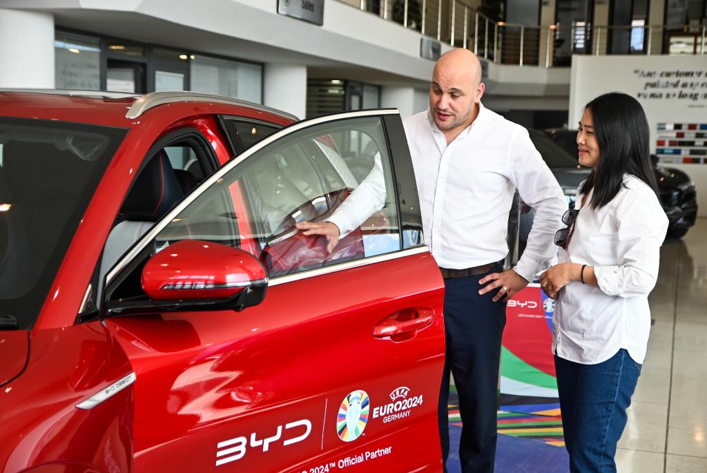 2024年5月29日，在马耳他比尔基卡拉，马耳他哈桑-扎米特汽车公司首席执行官德古阿拉（左）介绍一辆比亚迪纯电动汽车。新华社发（乔纳森·博格 摄）