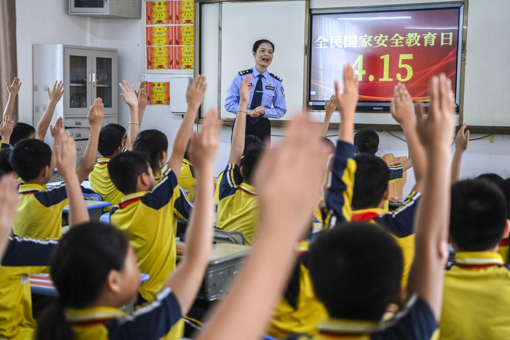 　　2024年4月15日，在广西兴业县一所小学内，公安民警在讲解国家安全相关知识的过程中与学生们互动。新华社记者 曹祎铭 摄